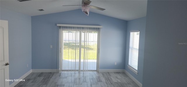 spare room featuring baseboards, vaulted ceiling, visible vents, and ceiling fan