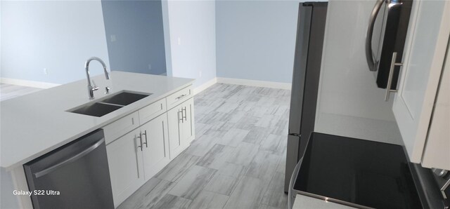 kitchen with light countertops, stainless steel dishwasher, white cabinetry, and a sink