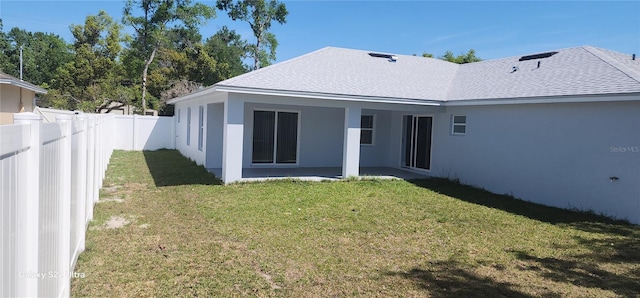 rear view of property with a yard, roof with shingles, a fenced backyard, and stucco siding