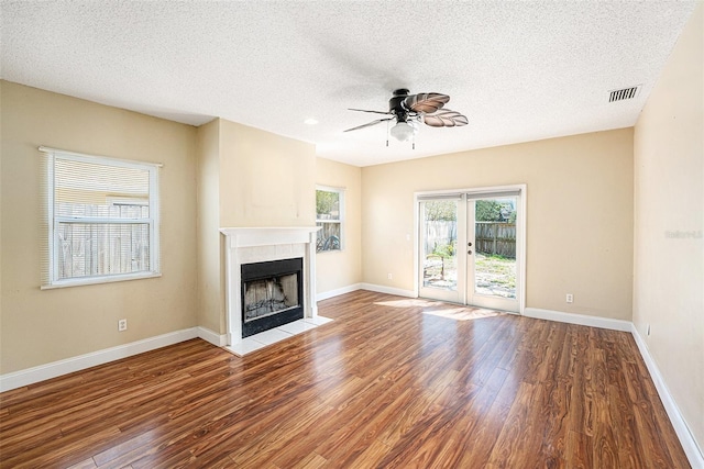 1366 Wexford Dr N, Palm Harbor, FL 34683 - unfurnished living room featuring a tiled fireplace, wood finished floors, a ceiling fan, and visible vents