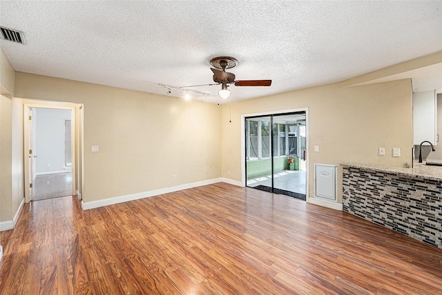 1366 Wexford Dr N, Palm Harbor, FL 34683 - unfurnished living room featuring visible vents, ceiling fan, wood finished floors, a textured ceiling, and a sink