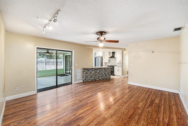 1366 Wexford Dr N, Palm Harbor, FL 34683 - unfurnished living room with wood finished floors, visible vents, baseboards, ceiling fan, and a textured ceiling