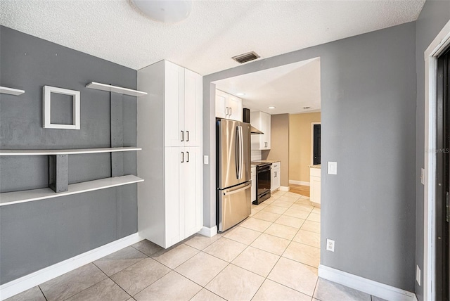 1366 Wexford Dr N, Palm Harbor, FL 34683 - kitchen featuring black / electric stove, visible vents, freestanding refrigerator, white cabinets, and wall chimney range hood