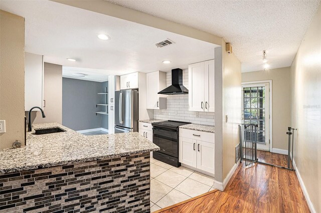 1366 Wexford Dr N, Palm Harbor, FL 34683 - kitchen featuring electric range, visible vents, a sink, freestanding refrigerator, and wall chimney range hood