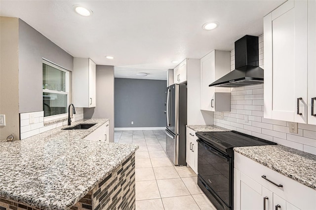 1366 Wexford Dr N, Palm Harbor, FL 34683 - kitchen with black range with electric cooktop, wall chimney range hood, light stone counters, freestanding refrigerator, and a sink