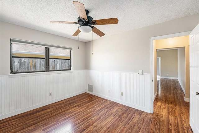 1366 Wexford Dr N, Palm Harbor, FL 34683 - empty room featuring wainscoting, a textured ceiling, wood finished floors, and a ceiling fan