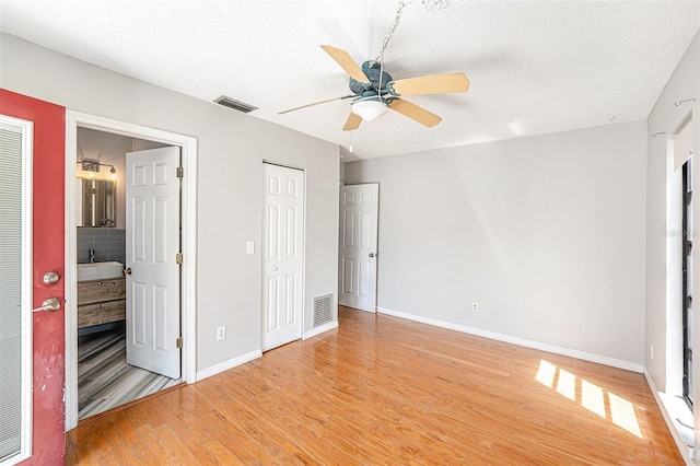 1366 Wexford Dr N, Palm Harbor, FL 34683 - unfurnished bedroom with light wood finished floors, visible vents, a textured ceiling, and baseboards