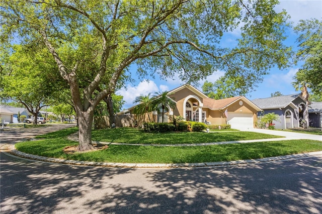 3627 Cypress Meadows Rd, Tampa, FL 33624 - view of front of house with stucco siding, fence, an attached garage, driveway, and a front lawn