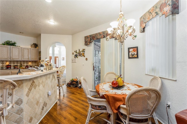 3627 Cypress Meadows Rd, Tampa, FL 33624 - dining space with arched walkways, dark wood-style floors, a notable chandelier, and a textured ceiling