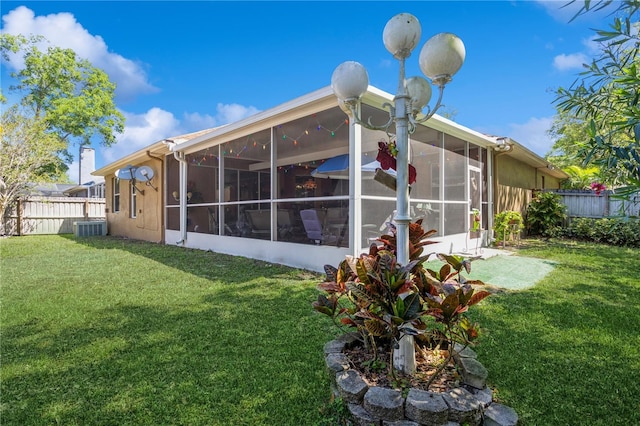 3627 Cypress Meadows Rd, Tampa, FL 33624 - rear view of property with a lawn, a sunroom, fence, and central AC unit