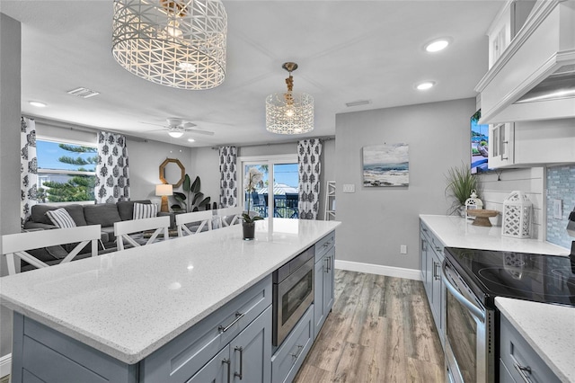 812 Gulf # 3, Indian Rocks Beach, FL 33785 - kitchen featuring light wood-type flooring, custom range hood, stainless steel appliances, gray cabinetry, and visible vents