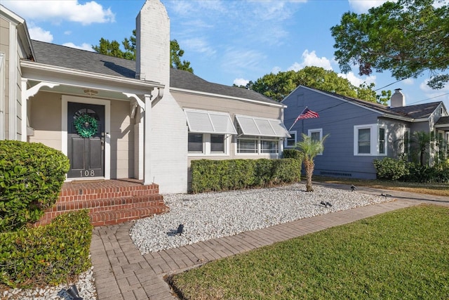 property entrance featuring a chimney and roof with shingles