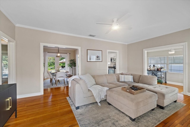 living room with light wood-type flooring, baseboards, visible vents, and a ceiling fan