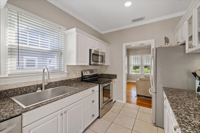 kitchen featuring light tile patterned flooring, a sink, white cabinetry, stainless steel appliances, and visible vents