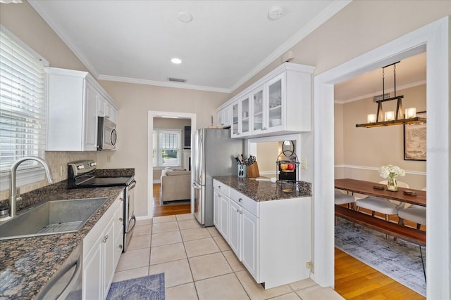 kitchen with glass insert cabinets, white cabinetry, a sink, and appliances with stainless steel finishes