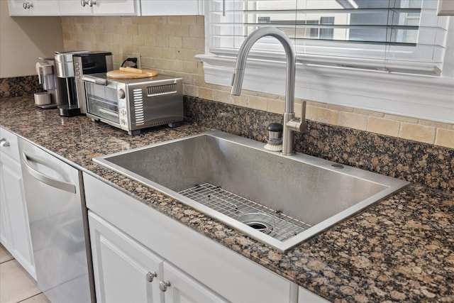 interior details featuring dishwasher, a sink, white cabinetry, and decorative backsplash