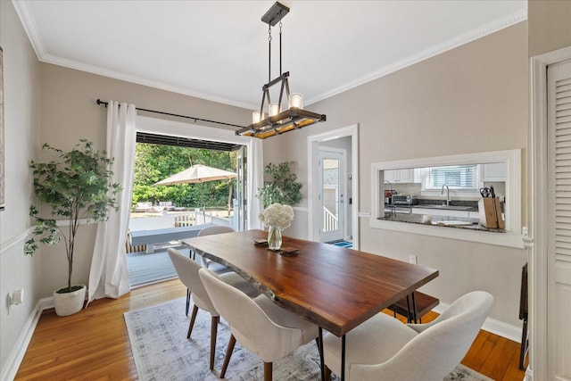 dining space featuring an inviting chandelier, crown molding, and light wood-style floors