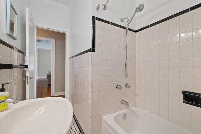 full bath featuring a sink, ornamental molding, tile walls, and shower / washtub combination