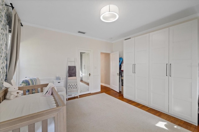 bedroom featuring wood finished floors, crown molding, a closet, and visible vents