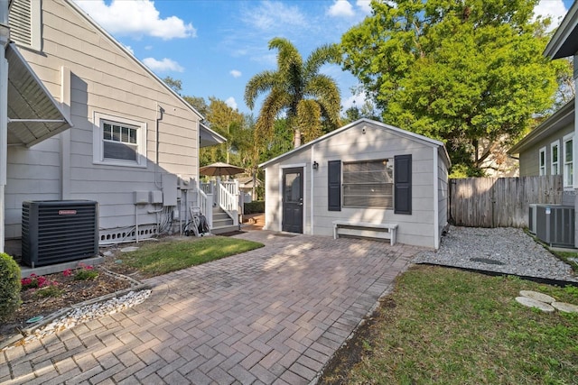 exterior space featuring an outdoor structure, central AC unit, fence, and a patio