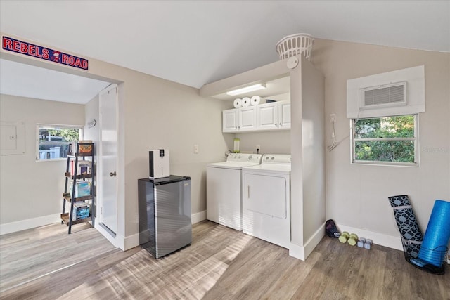 clothes washing area featuring cabinet space, washing machine and dryer, baseboards, and light wood finished floors