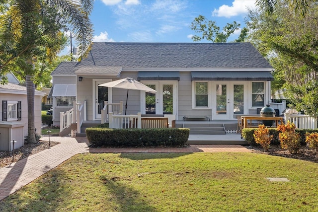 back of property featuring a lawn, a shingled roof, and french doors