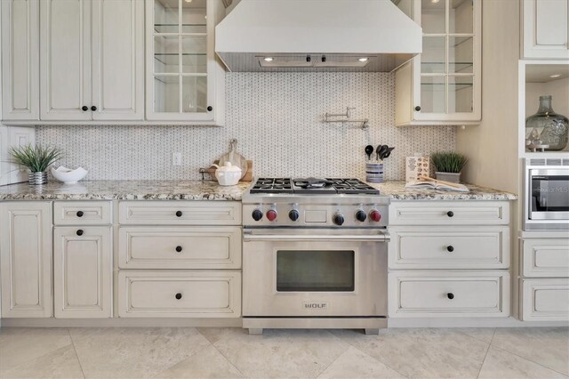 700 126th Ave, Treasure Island, FL 33706 - kitchen with glass insert cabinets, light stone countertops, custom exhaust hood, and stainless steel appliances