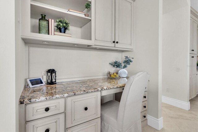 700 126th Ave, Treasure Island, FL 33706 - interior space with built in study area, open shelves, light tile patterned floors, baseboards, and light stone countertops