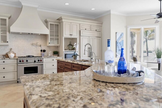 700 126th Ave, Treasure Island, FL 33706 - kitchen featuring high end range, custom exhaust hood, ceiling fan, tasteful backsplash, and a sink