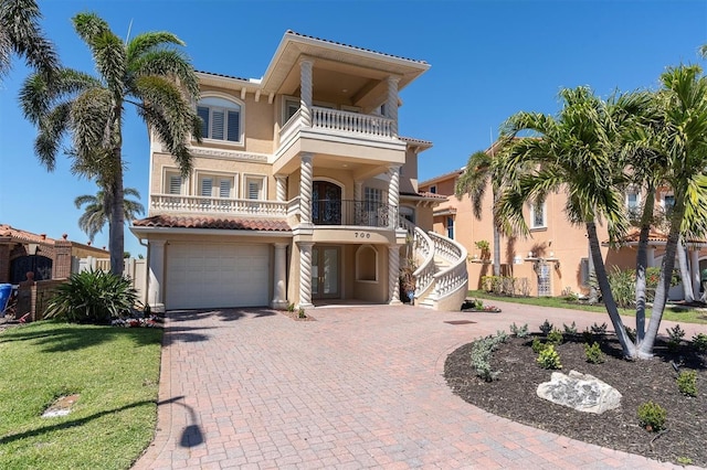 700 126th Ave, Treasure Island, FL 33706 - mediterranean / spanish-style home with stucco siding, stairway, an attached garage, a balcony, and decorative driveway