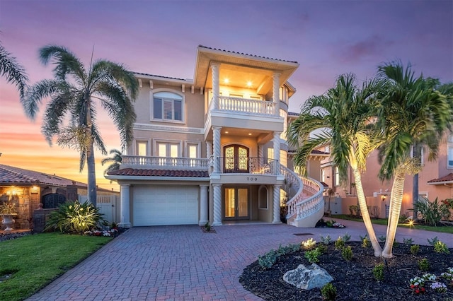 700 126th Ave, Treasure Island, FL 33706 - view of front of property featuring a balcony, decorative driveway, an attached garage, stucco siding, and french doors