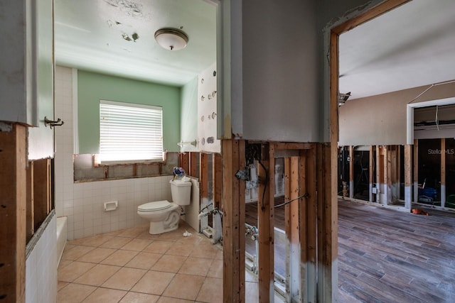 1591 N Dakota Ave NE, Saint Petersburg, FL 33703 - bathroom featuring toilet, tile patterned floors, tile walls, and wainscoting