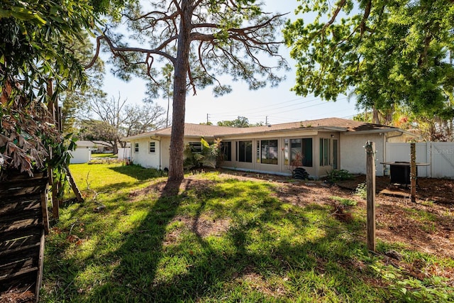 1591 N Dakota Ave NE, Saint Petersburg, FL 33703 - rear view of property with fence, stucco siding, and a yard