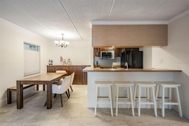 107 S Obrien St Unit 117, Tampa, FL 33609 - kitchen featuring stainless steel microwave, ornamental molding, a peninsula, freestanding refrigerator, and an inviting chandelier