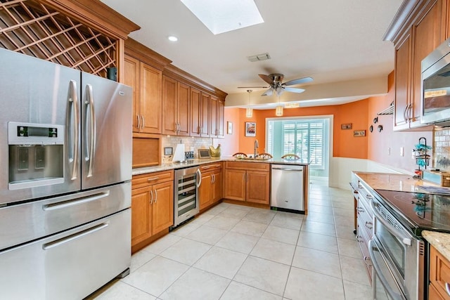 3545 Seaway Dr, New Port Richey, FL 34652 - kitchen featuring beverage cooler, a sink, stainless steel appliances, a peninsula, and a skylight