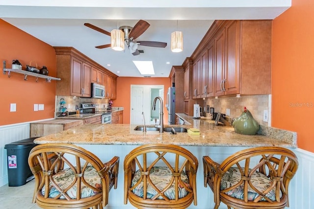 3545 Seaway Dr, New Port Richey, FL 34652 - kitchen with a wainscoted wall, a peninsula, ceiling fan, a sink, and appliances with stainless steel finishes