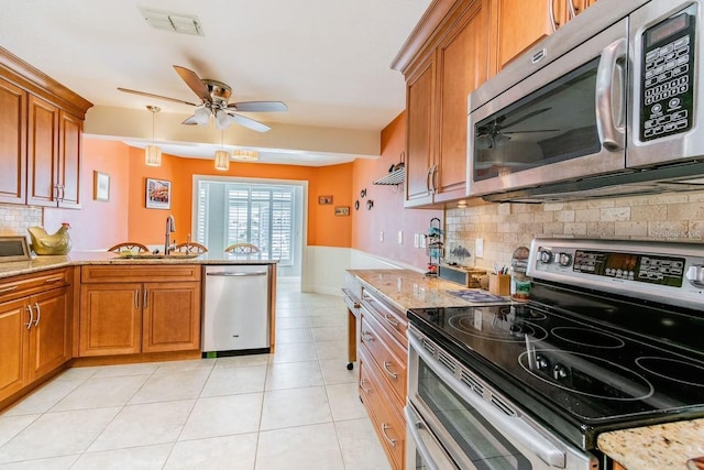 3545 Seaway Dr, New Port Richey, FL 34652 - kitchen with ceiling fan, brown cabinets, a peninsula, stainless steel appliances, and a sink