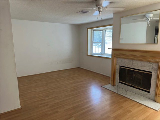 9741 Scenic Dr, Port Richey, FL 34668 - unfurnished living room featuring a ceiling fan, wood finished floors, a textured ceiling, and a fireplace