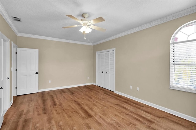 4404 Lake In The Woods Dr, Spring Hill, FL 34607 - unfurnished bedroom featuring multiple windows, light wood-type flooring, ornamental molding, a textured ceiling, and baseboards