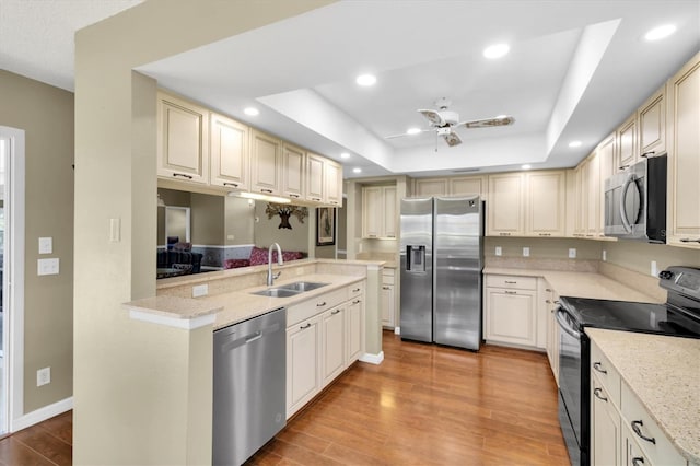 7472 Clearmeadow Dr, Spring Hill, FL 34606 - kitchen featuring a ceiling fan, a sink, appliances with stainless steel finishes, a raised ceiling, and light wood-type flooring