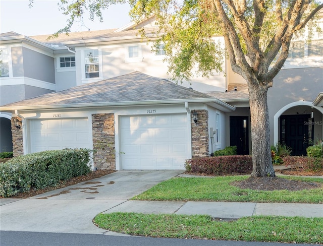 view of property featuring driveway, stucco siding, and stone siding