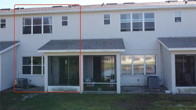 rear view of property with a sunroom, central air condition unit, and stucco siding
