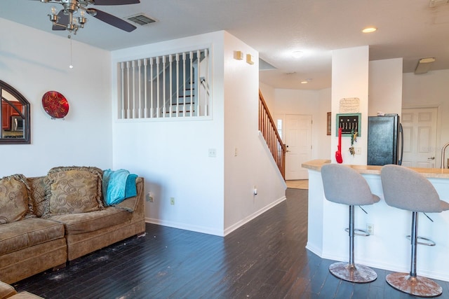 living area featuring stairway, visible vents, a ceiling fan, baseboards, and dark wood-style flooring