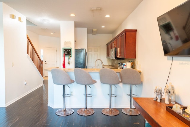 kitchen featuring decorative backsplash, freestanding refrigerator, stainless steel microwave, a peninsula, and recessed lighting