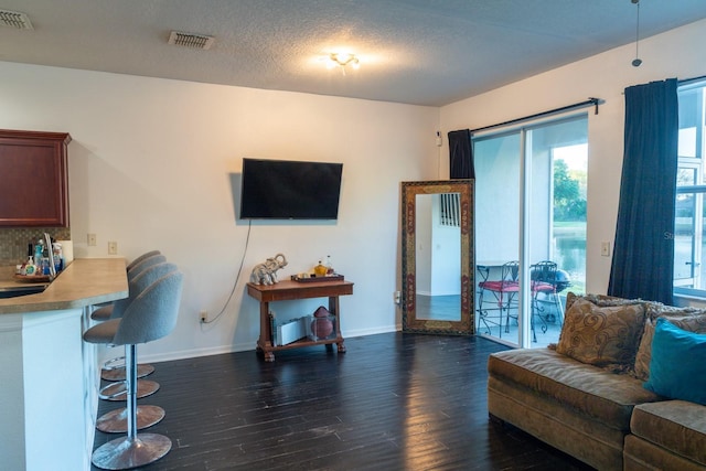 living area featuring dark wood-style floors, baseboards, and visible vents