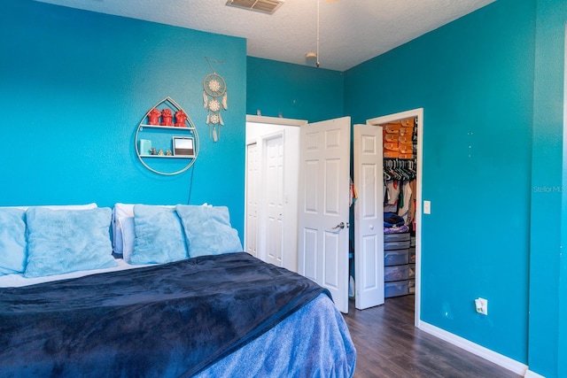 bedroom featuring dark wood-type flooring, a closet, baseboards, and a walk in closet