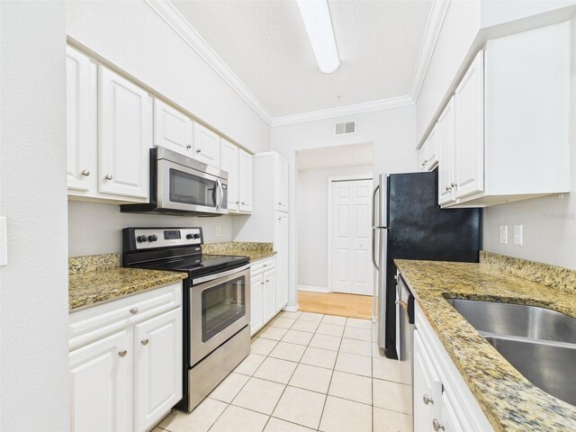 1810 E Palm Ave Unit 6104, Tampa, FL 33605 - kitchen featuring appliances with stainless steel finishes, crown molding, light tile patterned flooring, and white cabinets