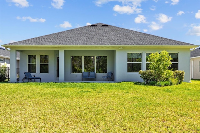 rear view of house with a yard, a shingled roof, and stucco siding
