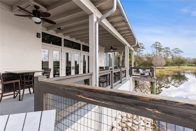 wooden terrace featuring a water view, a ceiling fan, and french doors