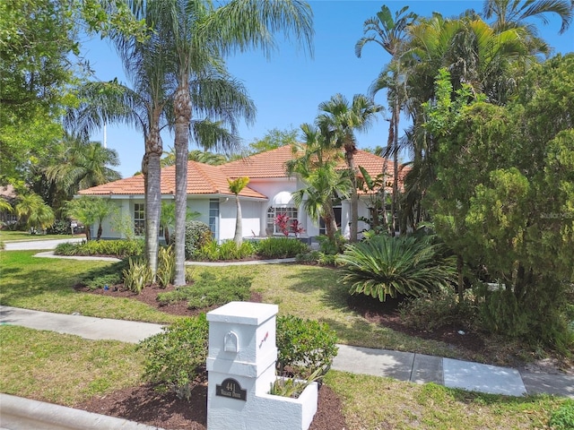 441 Village Dr, Tarpon Springs, FL 34689 - mediterranean / spanish-style home with a tiled roof, a front lawn, and stucco siding